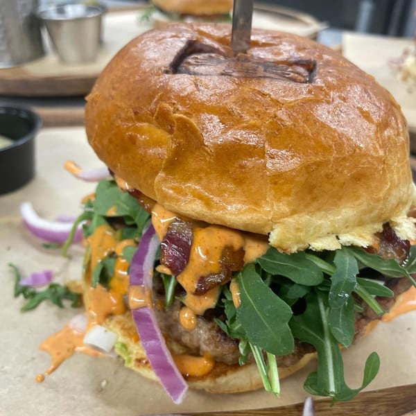 Close-up of a Brunch House 1850 burger with arugula, red onion, and special sauce.