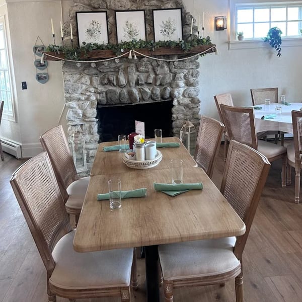 Brunch House 1850 dining room with wooden tables, cane-back chairs, and a stone fireplace.