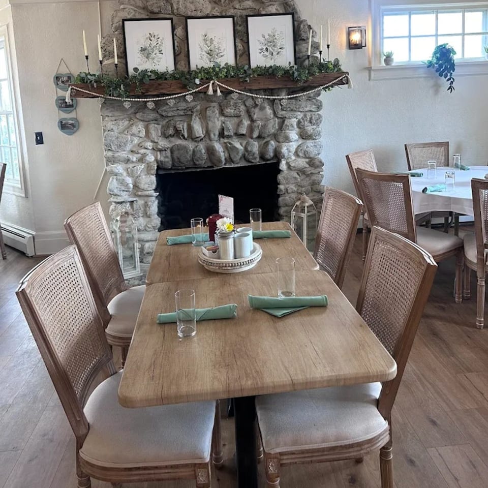 Brunch House 1850 dining room with wooden tables, cane-back chairs, and a stone fireplace.