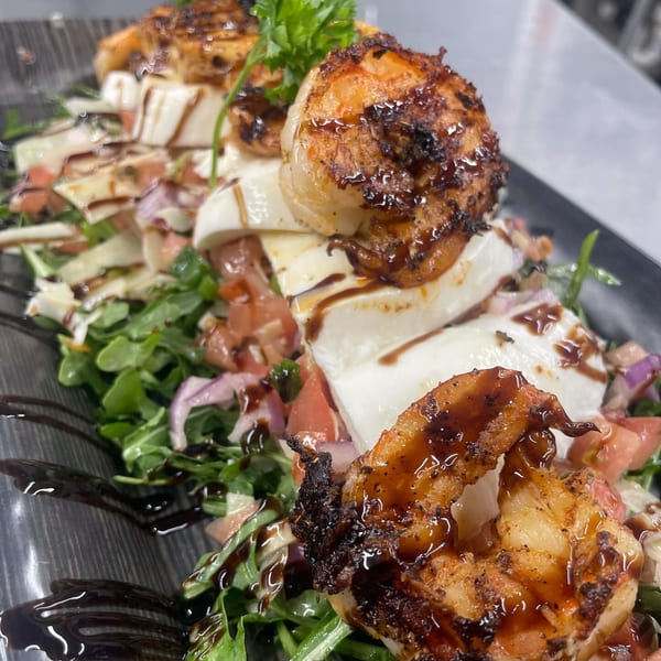 Grilled shrimp and mozzarella salad with arugula, tomatoes, and balsamic glaze at Brunch House 1850.