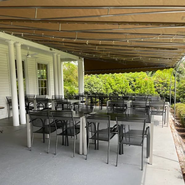 Outdoor patio dining area at Brunch House 1850 with tables, chairs, and a retractable awning.